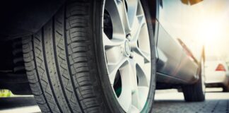 Close-up of a tire on a silver sedan. The tires look new and have a deep, detailed tread, which shows they are in good shape.